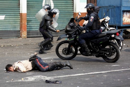 A police officer lies on the street after being run over by a bus during a protest against the increase in the price of public transport in San Cristobal