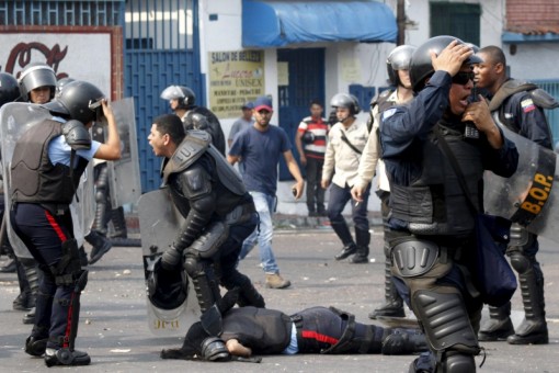 A police officer talks via radio next to a partner run over by a bus during a protest against the increase in the price of public transport in San Cristobal
