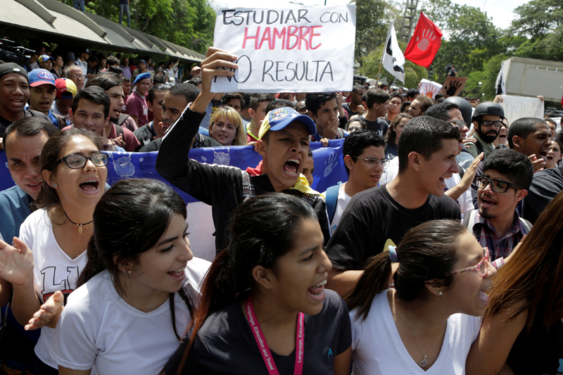 Student protesters shout during a rally to demand increased university funding in Caracas, Venezuela, May 26, 2016. The placard reads "Studying with hunger does not pay off". REUTERS/Marco Bello
