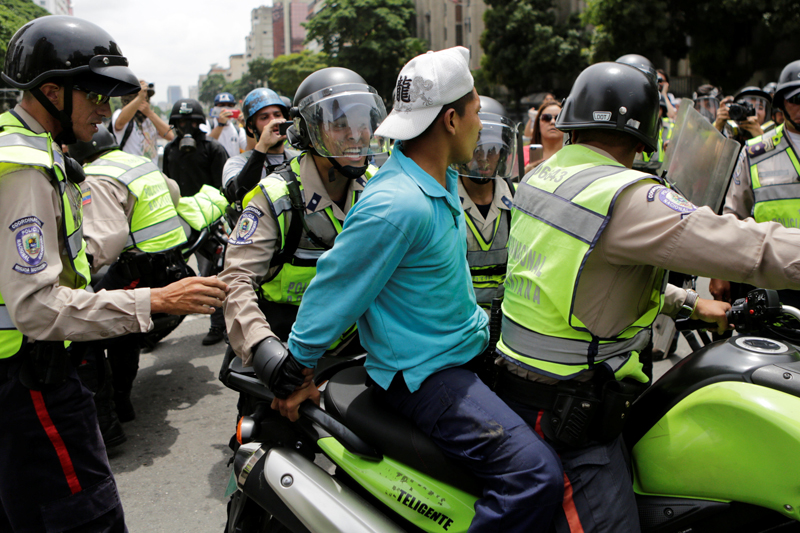 Riot police officers detain a demonstrator on a motorcycle during clashes with opposition supporters in a rally to demand a referendum to remove President Nicolas Maduro in Caracas, Venezuela, May 18, 2016. REUTERS/Marco Bello