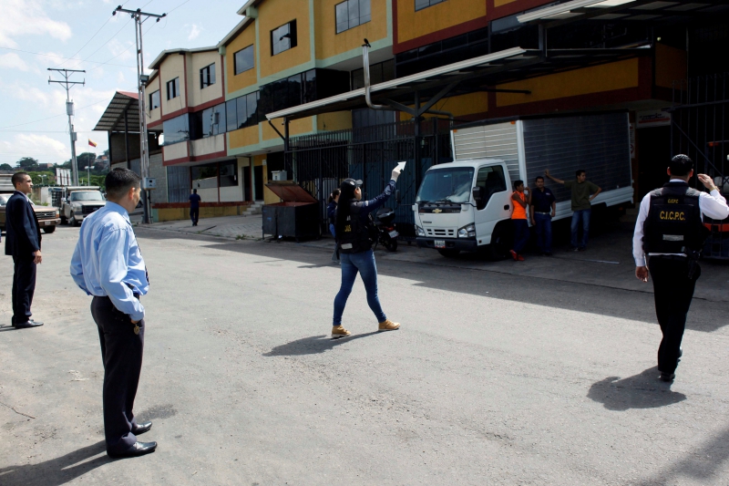 Police officers and criminal investigators inspect the area where a woman was shot when looters raided state food warehouses, in San Cristobal, Venezuela, June 6, 2016. REUTERS/Carlos Eduardo Ramirez