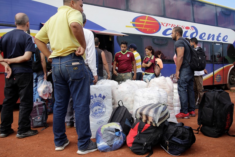 People stand next to bags filled with staple items and their luggage while they wait for transportation, after arriving from Brazil, at the bus terminal in Santa Elena de Uairen, Venezuela August 2, 2016. Picture taken August 2, 2016. REUTERS/William Urdaneta          FOR EDITORIAL USE ONLY. NO RESALES. NO ARCHIVES.