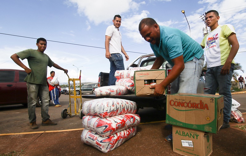 Men load boxes of food onto the back of a pick-up truck, after arriving from Brazil, in front of the bus terminal in Santa Elena de Uairen, Venezuela August 2, 2016. Picture taken August 2, 2016. REUTERS/William Urdaneta FOR EDITORIAL USE ONLY. NO RESALES. NO ARCHIVES.