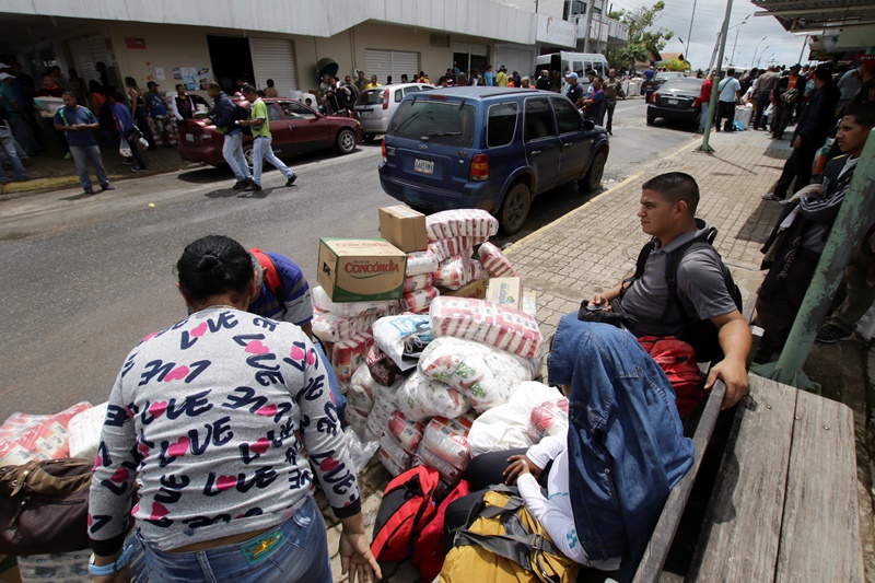 People sit next to bags filled with staple items while they wait for transportation in Pacaraima, Brazil August 3, 2016. Picture taken August 3, 2016. REUTERS/William Urdaneta FOR EDITORIAL USE ONLY. NO RESALES. NO ARCHIVES.