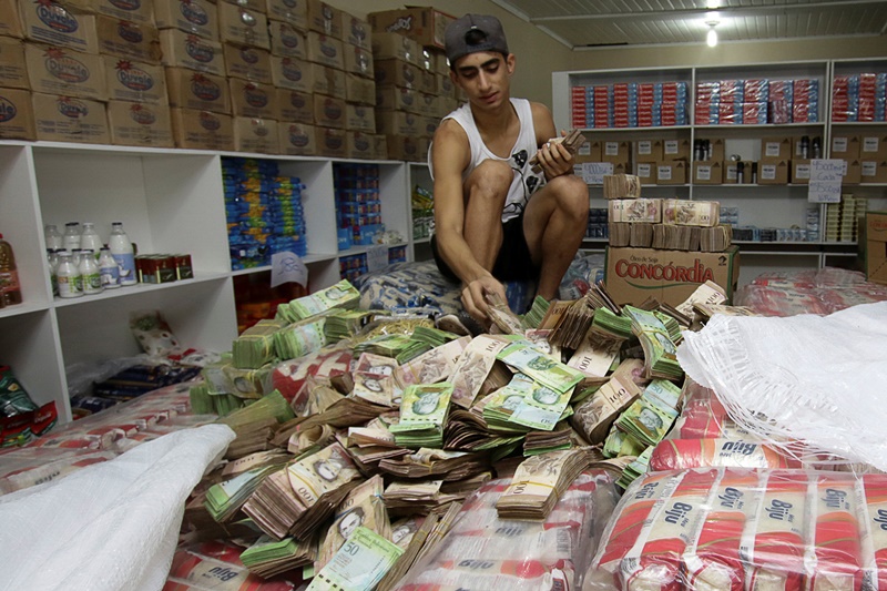 A man counts Venezuelan bolivar notes at a store that sells staple items and food in Pacaraima, Brazil August 3, 2016. Picture taken August 3, 2016. REUTERS/William Urdaneta FOR EDITORIAL USE ONLY. NO RESALES. NO ARCHIVES.