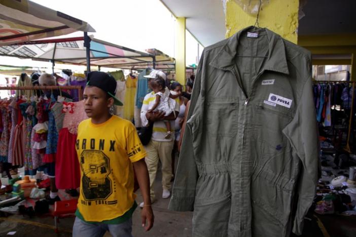 A boy walks past a PDVSA's overall for sale at a market in Maracaibo